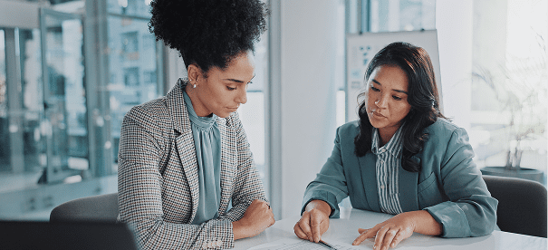 Two women discussing documents at table.