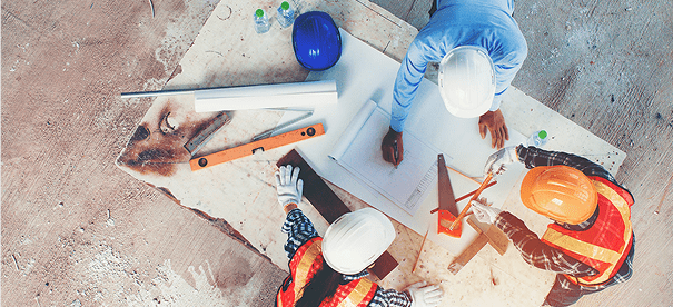 Construction workers reviewing blueprints on site.