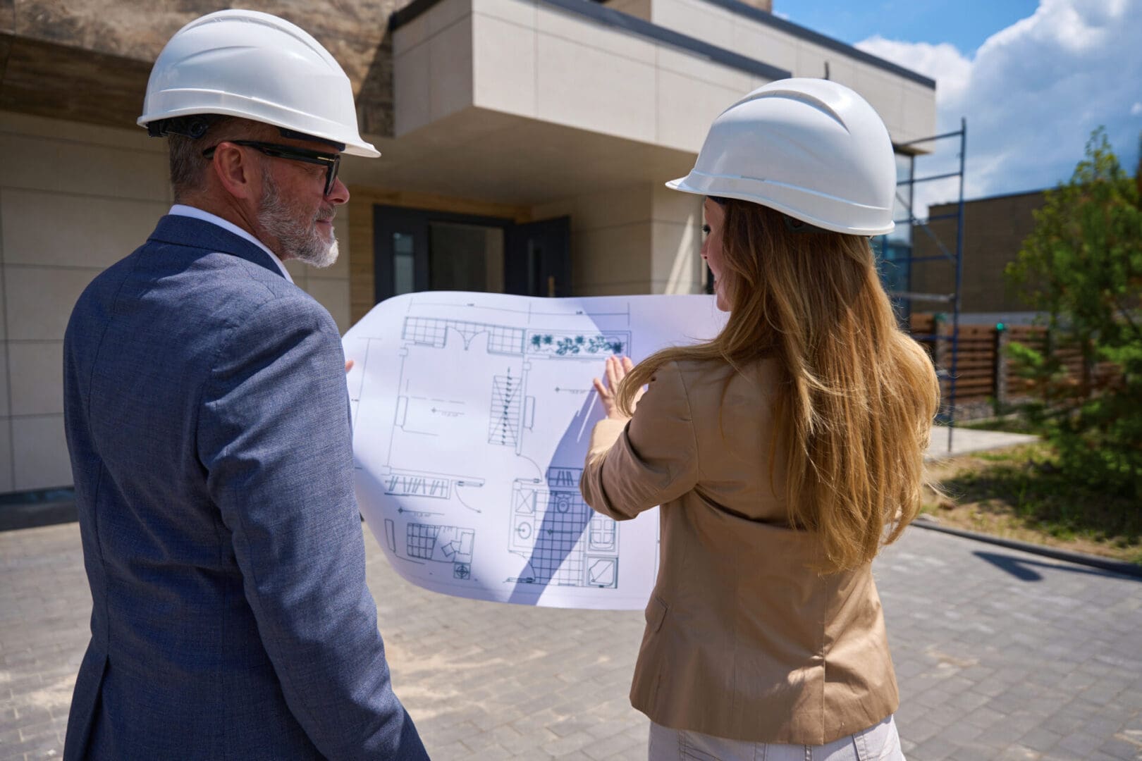 Architects reviewing blueprints outside a building site.